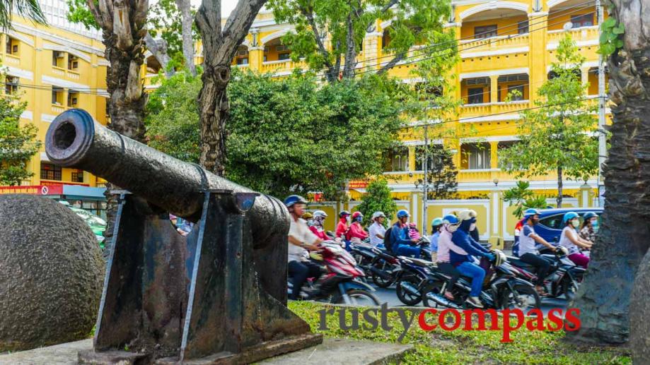 Cannons on the waterfront. Saigon with old French building in...