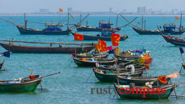 Fishing boats front a modern city.