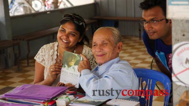 Tuol Sleng survivor Bou Meng poses for tourists.